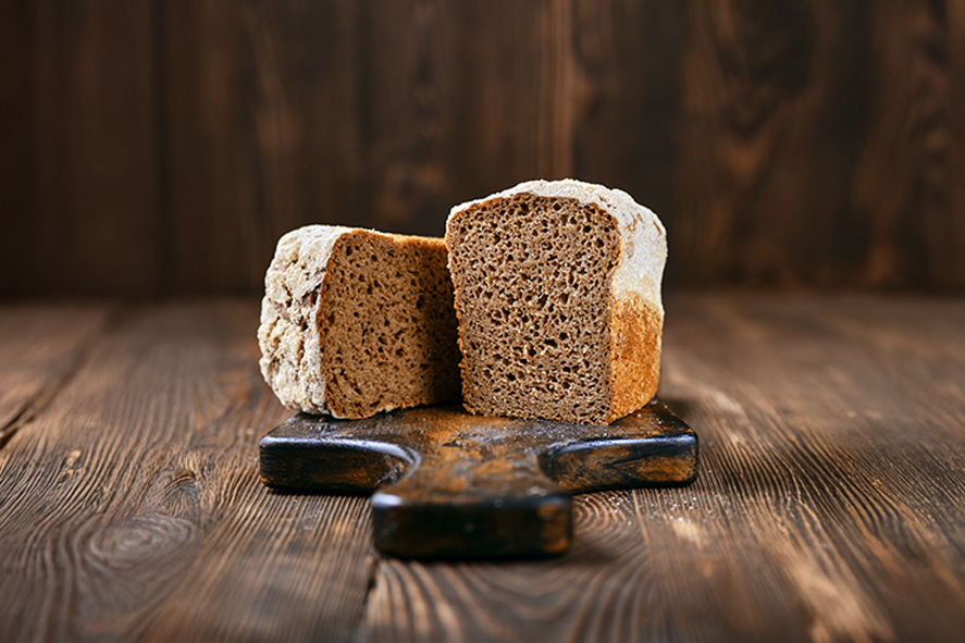 Chleb orkiszowy na drożdżach pokrojony na desce drewnianej